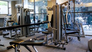 A gym with various exercise equipment, large windows, and a carpeted floor. - FuramaXclusive Sukhumvit (Bangkok)