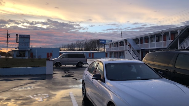A motel with a two-story building, a parking lot with cars, and a sunset sky. - New Sea Breeze Motel (Pleasantville)