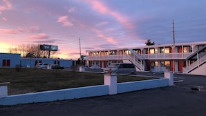 A motel with a two-story structure, a parking lot, and a Walmart sign in the background. - New Sea Breeze Motel (Pleasantville)