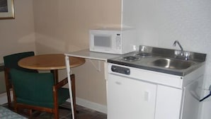 A compact kitchenette with a microwave, sink, and stove. - New Sea Breeze Motel (Pleasantville)