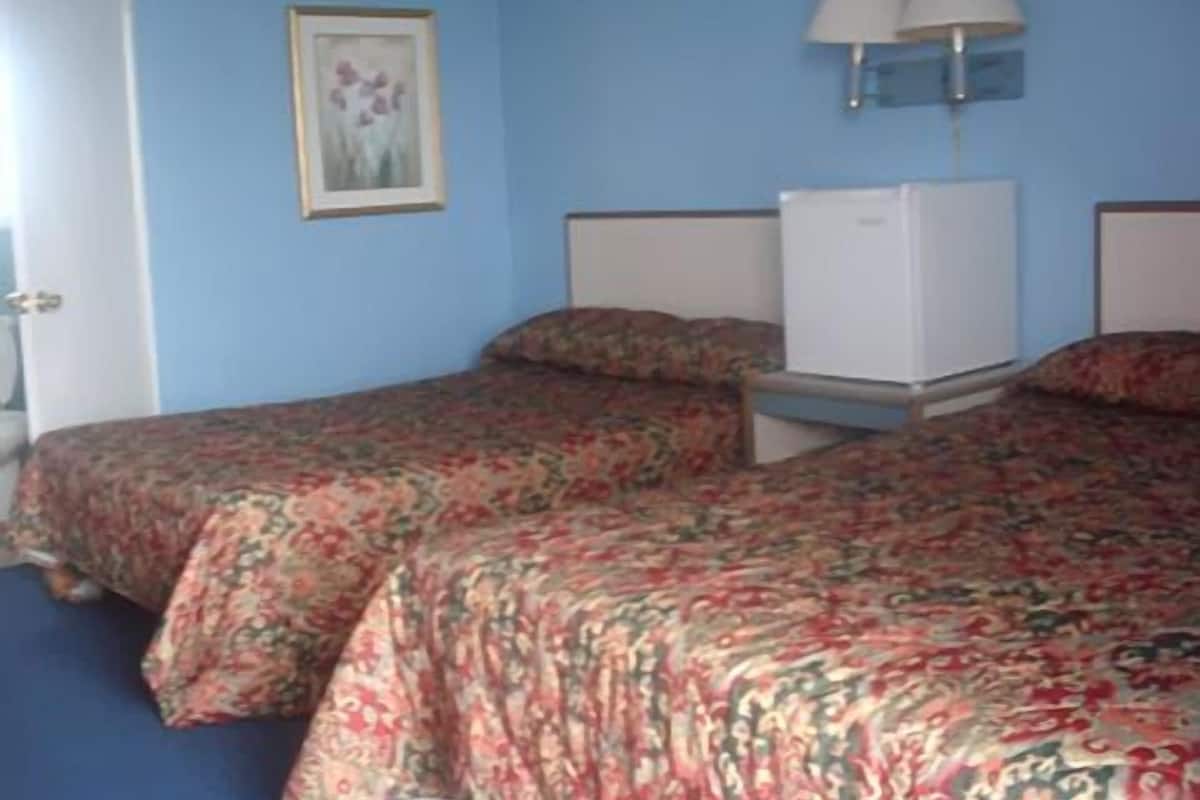Une chambre avec deux lits, un bureau et une lampe.