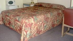 A bed with a floral bedspread, a bedside lamp, and a microwave on a nightstand. - New Sea Breeze Motel (Pleasantville)