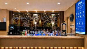 A bar area with a counter, stools, a digital menu board, and a clock.