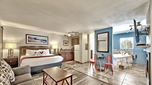 A hotel room with a bed, a desk, a chair, a bathroom with a bathtub, and a TV mounted on the wall. - Heavenly Inn (South Lake Tahoe)
