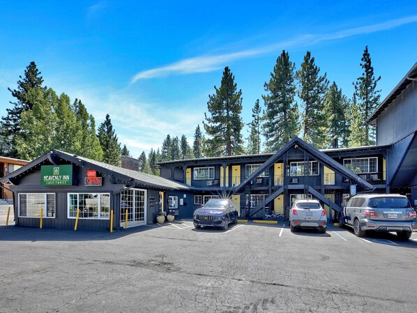 A hotel with a sign reading "Heavenly Inn Lake Tahoe" and a wheelchair accessibility symbol. There are two cars parked in front. - Heavenly Inn (South Lake Tahoe)