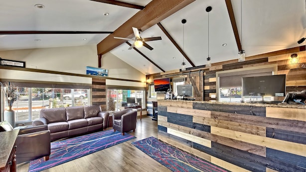 A spacious living area with a modern design, featuring a large sofa, a coffee table, and a wooden accent wall. - Heavenly Inn (South Lake Tahoe)