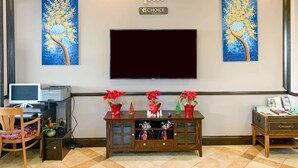 A hotel lobby with a television, a desk with a computer, and decorative vases. - Rodeway Inn Sun City Center (Sun City Center)