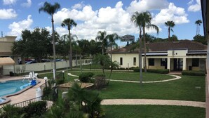 A hotel with a swimming pool, palm trees, and a well-maintained lawn. - Rodeway Inn Sun City Center (Sun City Center)