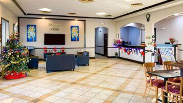 A hotel lobby with a Christmas tree, seating area, reception desk, and a wall clock.
