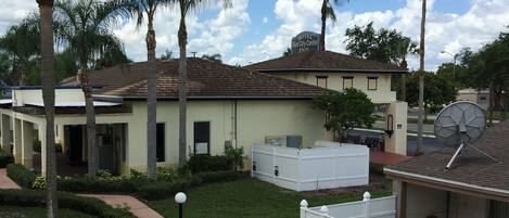 A hotel with a flat roof, a fenced yard, and palm trees.