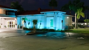 A modern building with a red roof, large windows, and a parking lot with marked spaces. - Rodeway Inn Sun City Center (Sun City Center)