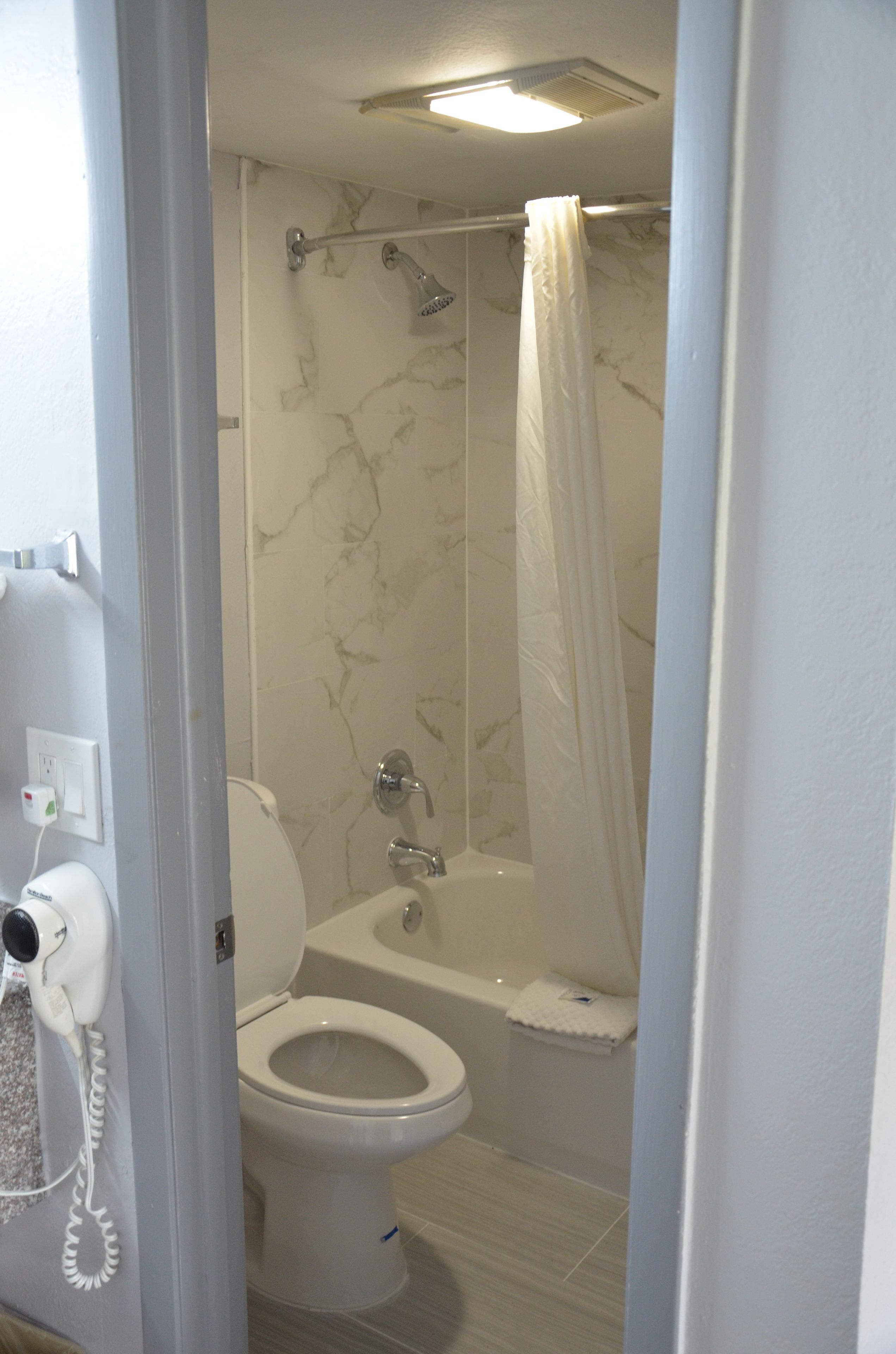 Une salle de bain comprenant des toilettes, une douche avec un rideau et une baignoire.
