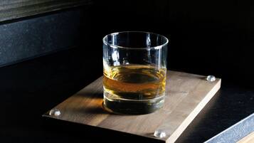 Un vaso de líquido ámbar sobre un posavasos de madera con tornillos metálicos.