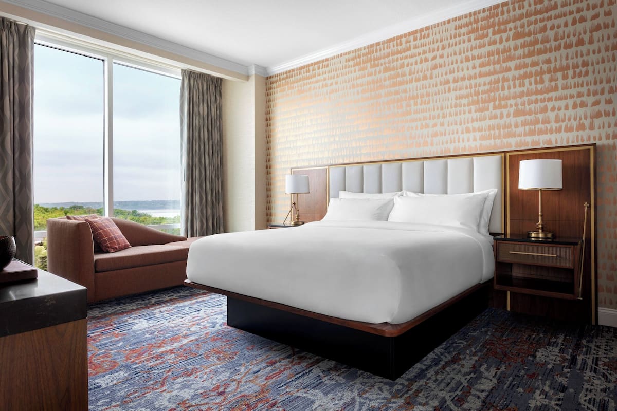 Een hotelkamer met een groot bed, een bank, een bureau en uitzicht op het omliggende landschap.