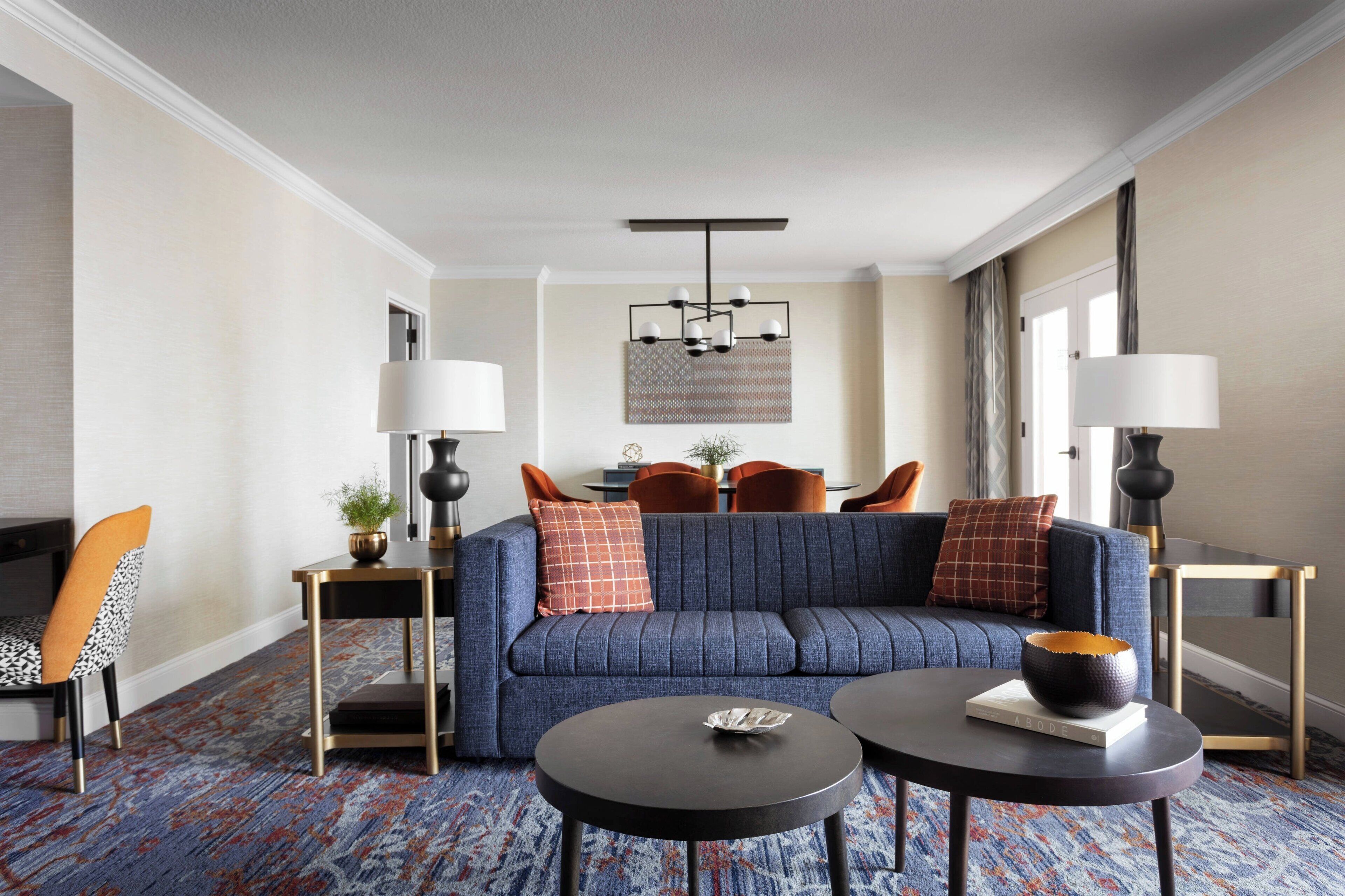 A modern living room with a blue sofa, two round tables, and a chandelier.