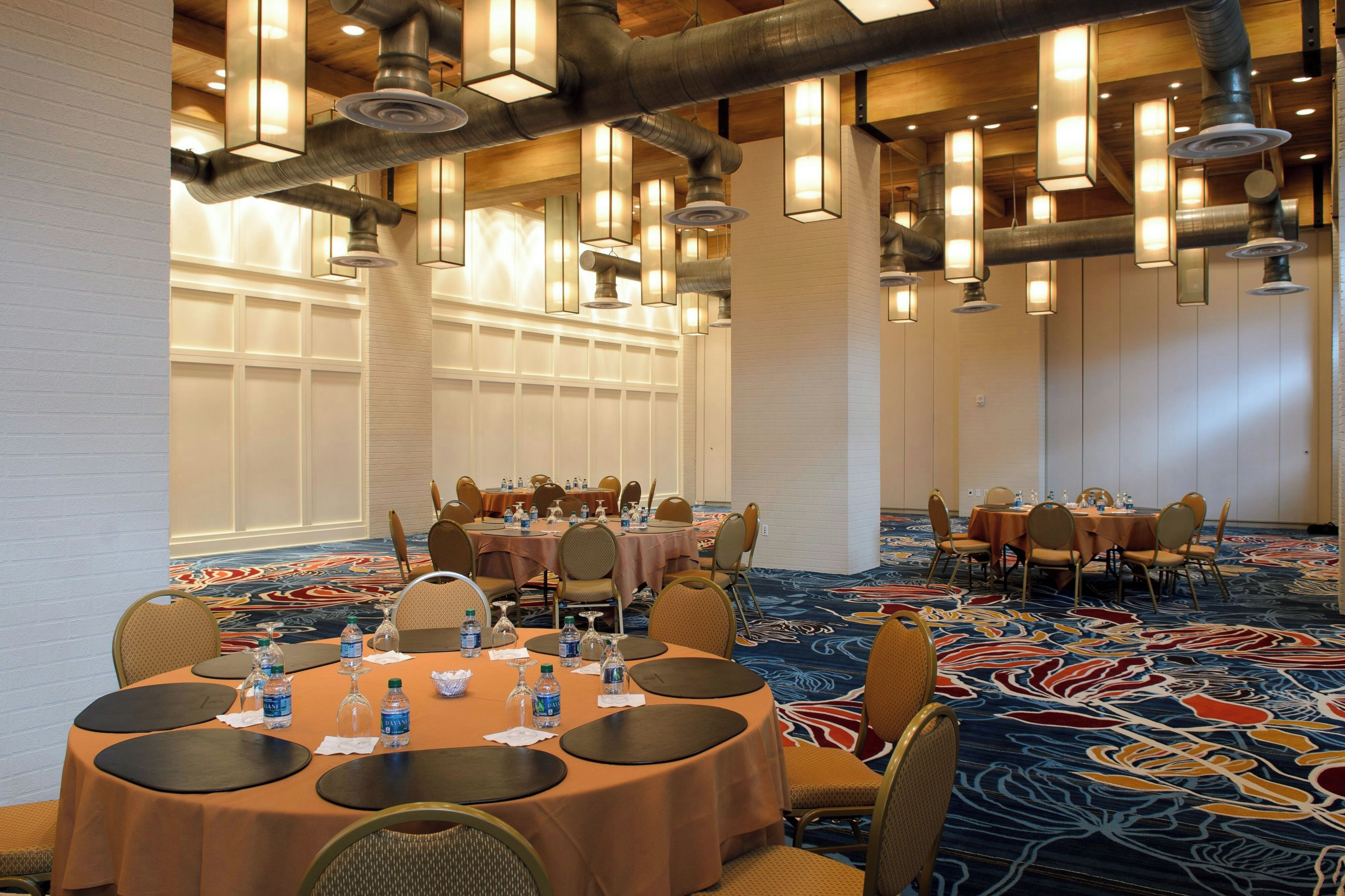 A conference room with round tables, chairs, and water bottles.
