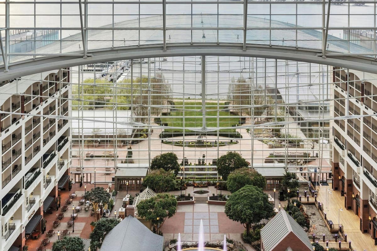 Een hoog hotel met meerdere verdiepingen, een centrale binnenplaats met een fontein en uitzicht op een brug over een rivier.