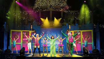 A stage with performers in colorful costumes, a Christmas tree, and a festive backdrop.