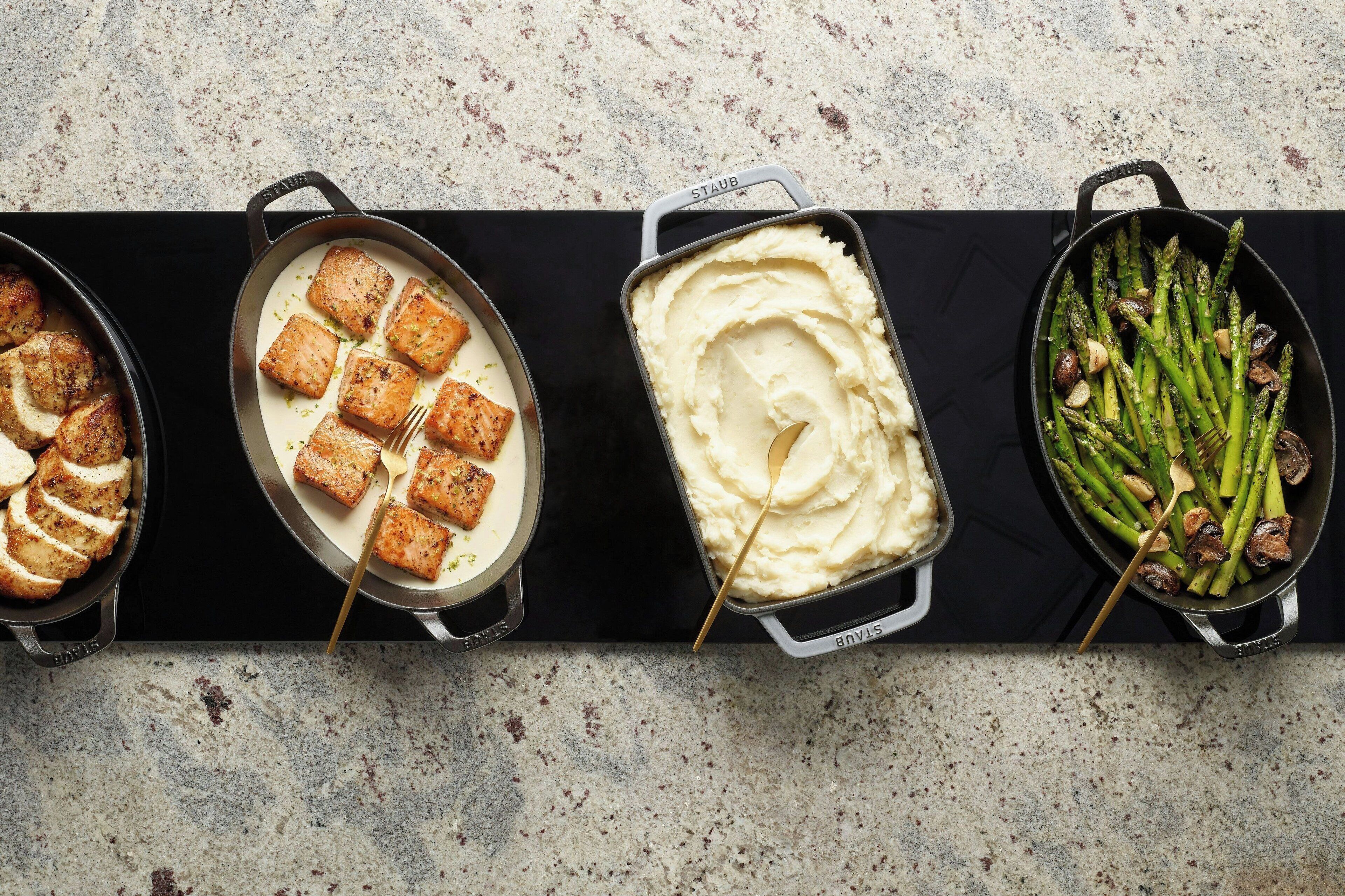 Cuatro platos: pollo a la parrilla, puré de papas y espárragos asados.
