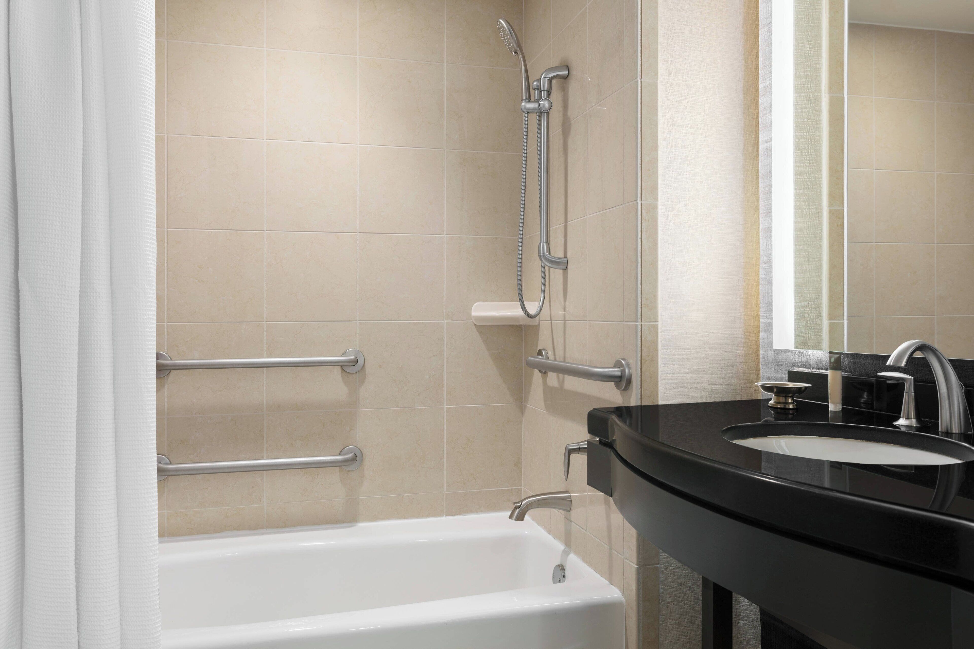 A modern bathroom with a bathtub, a shower, and a sink with a mirror.
