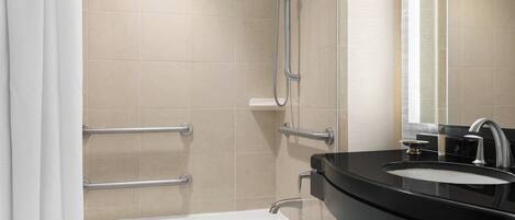 A modern bathroom with a bathtub, a shower, and a sink with a mirror.