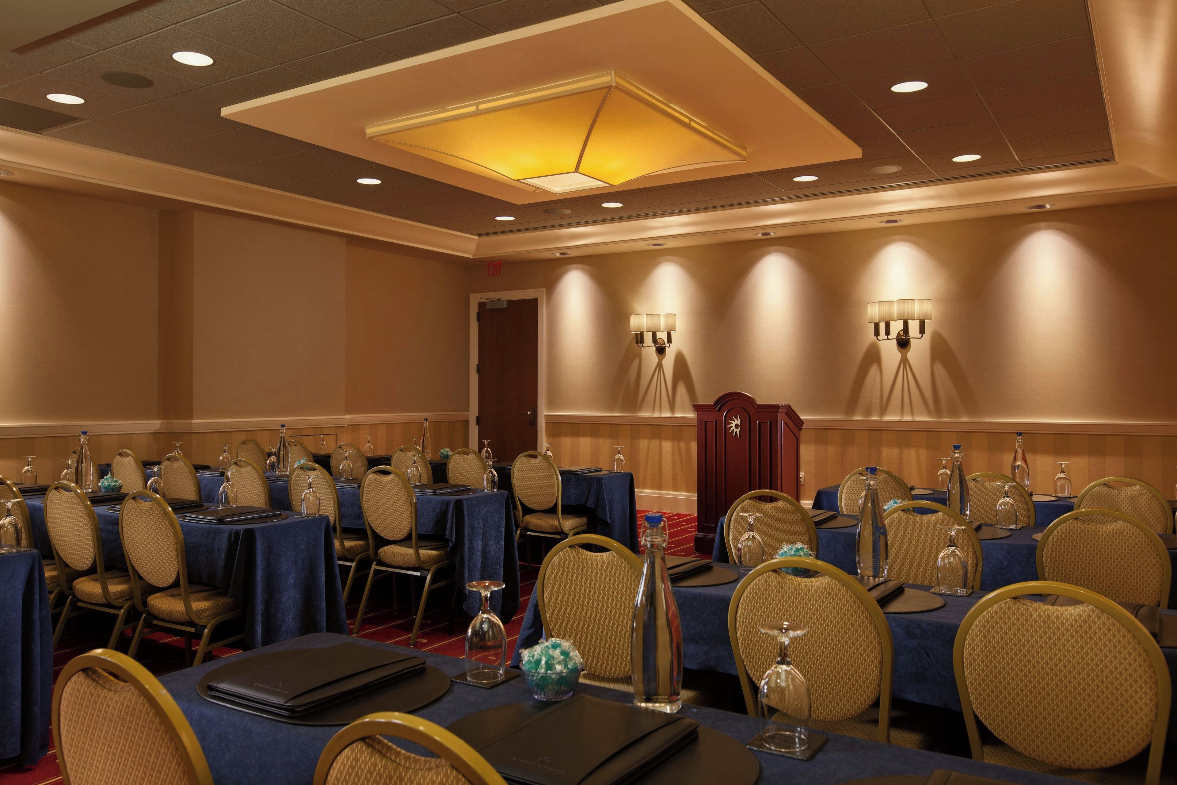 A conference room with round tables, chairs, and a red carpet.