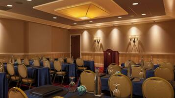 A conference room with round tables, chairs, and a red carpet.