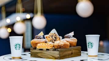 A tray of assorted pastries and two Starbucks cups on a table.