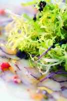 A close-up of a salad with various greens and purple elements.