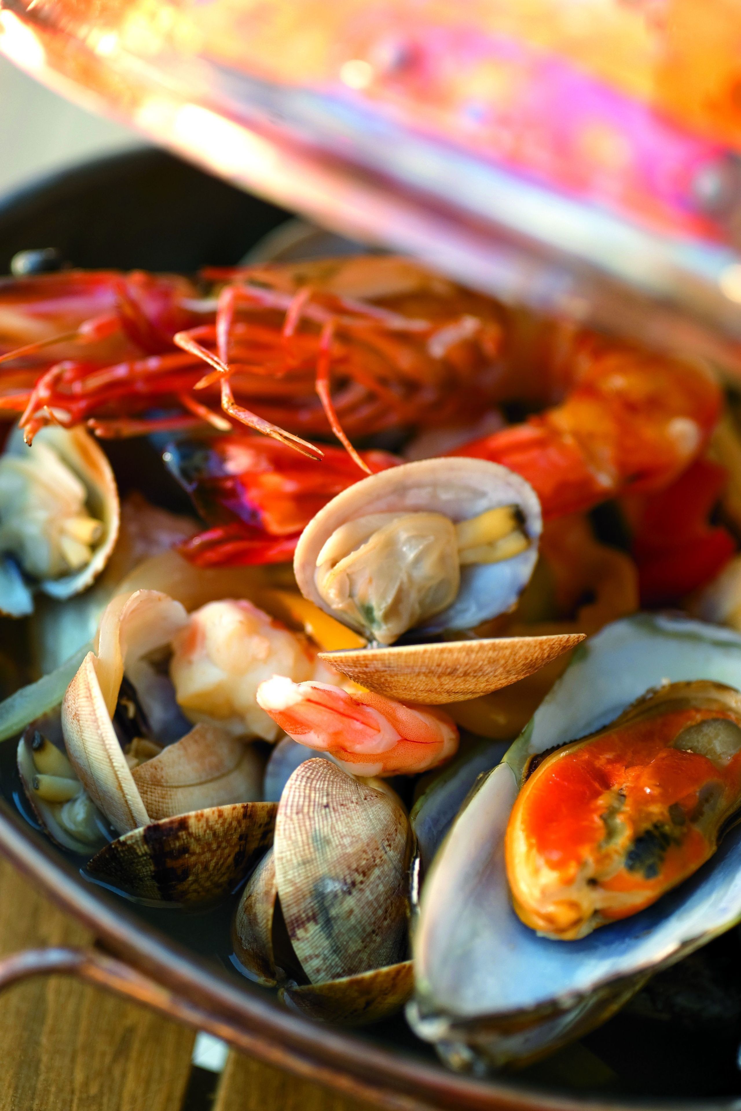 Primer plano de un plato de mariscos con almejas y camarones.