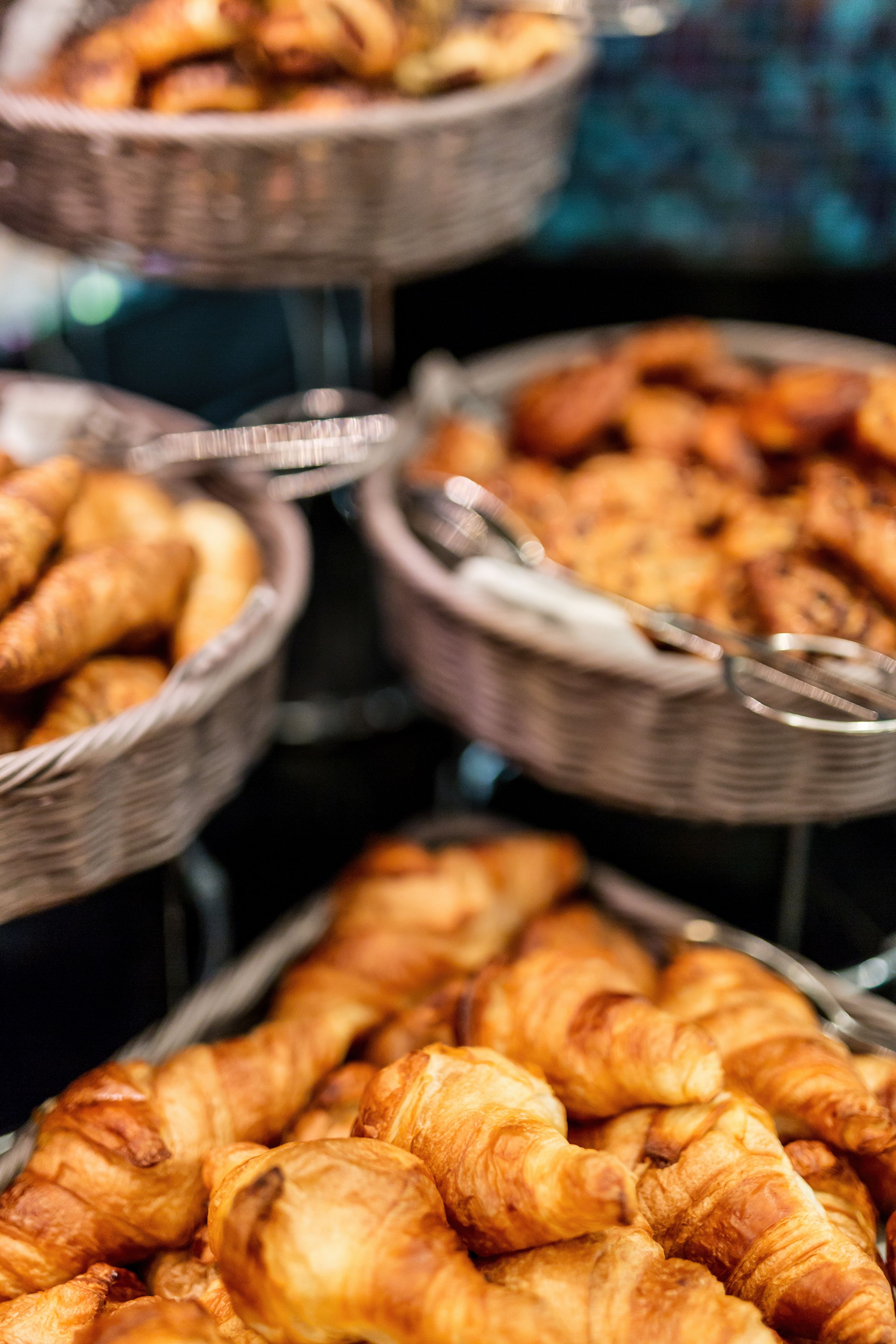 A display of various baked goods, including croissants and other pastries, arranged in baskets and trays.