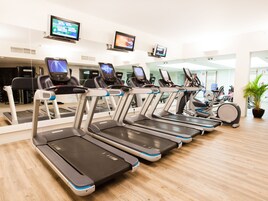 A row of treadmills in a gym with digital screens above them.