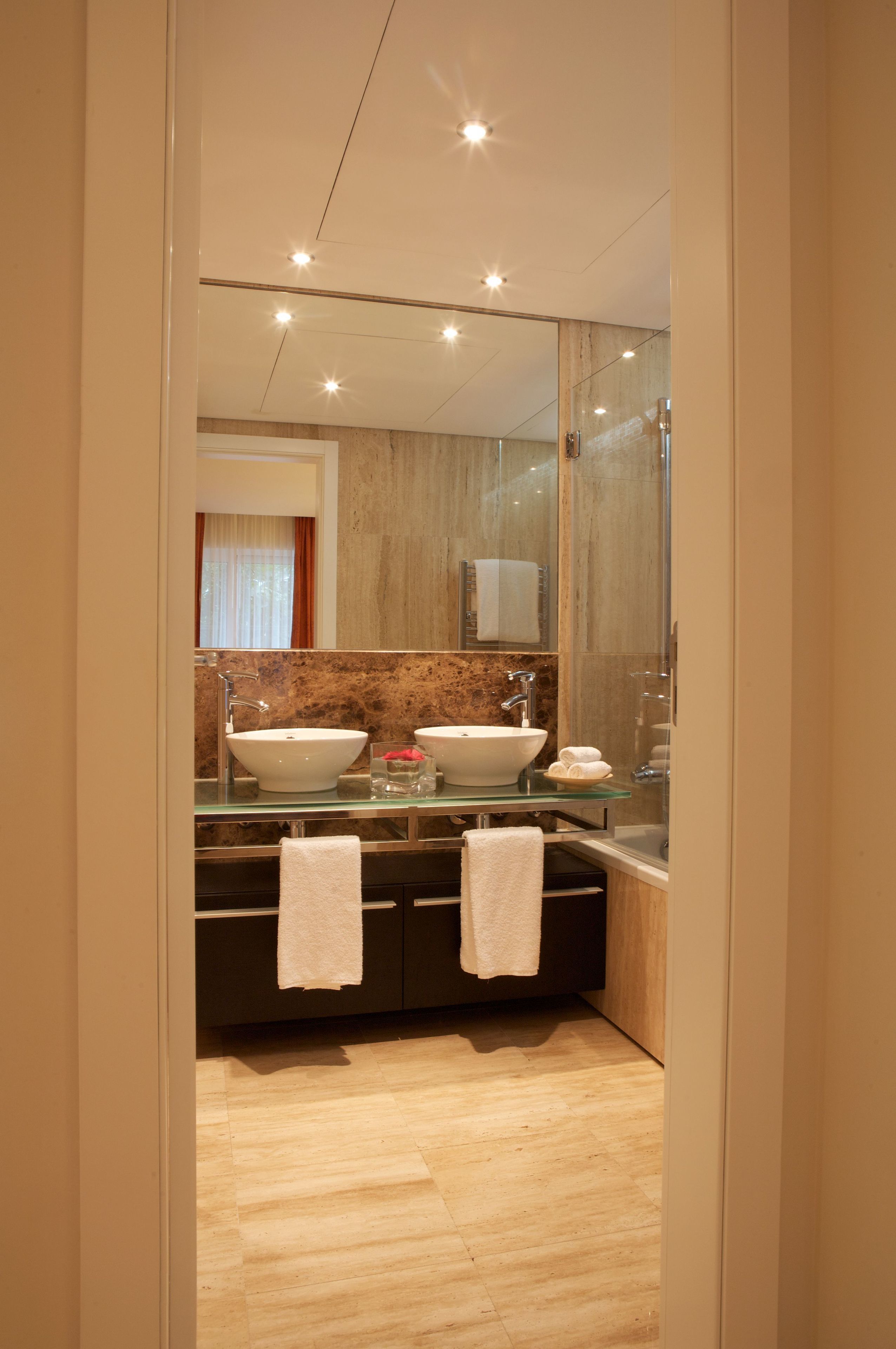 Une salle de bain moderne avec deux lavabos, une douche à l’italienne en verre et un grand miroir.