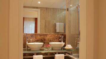 A modern bathroom with two sinks, a glass shower enclosure, and a large mirror.