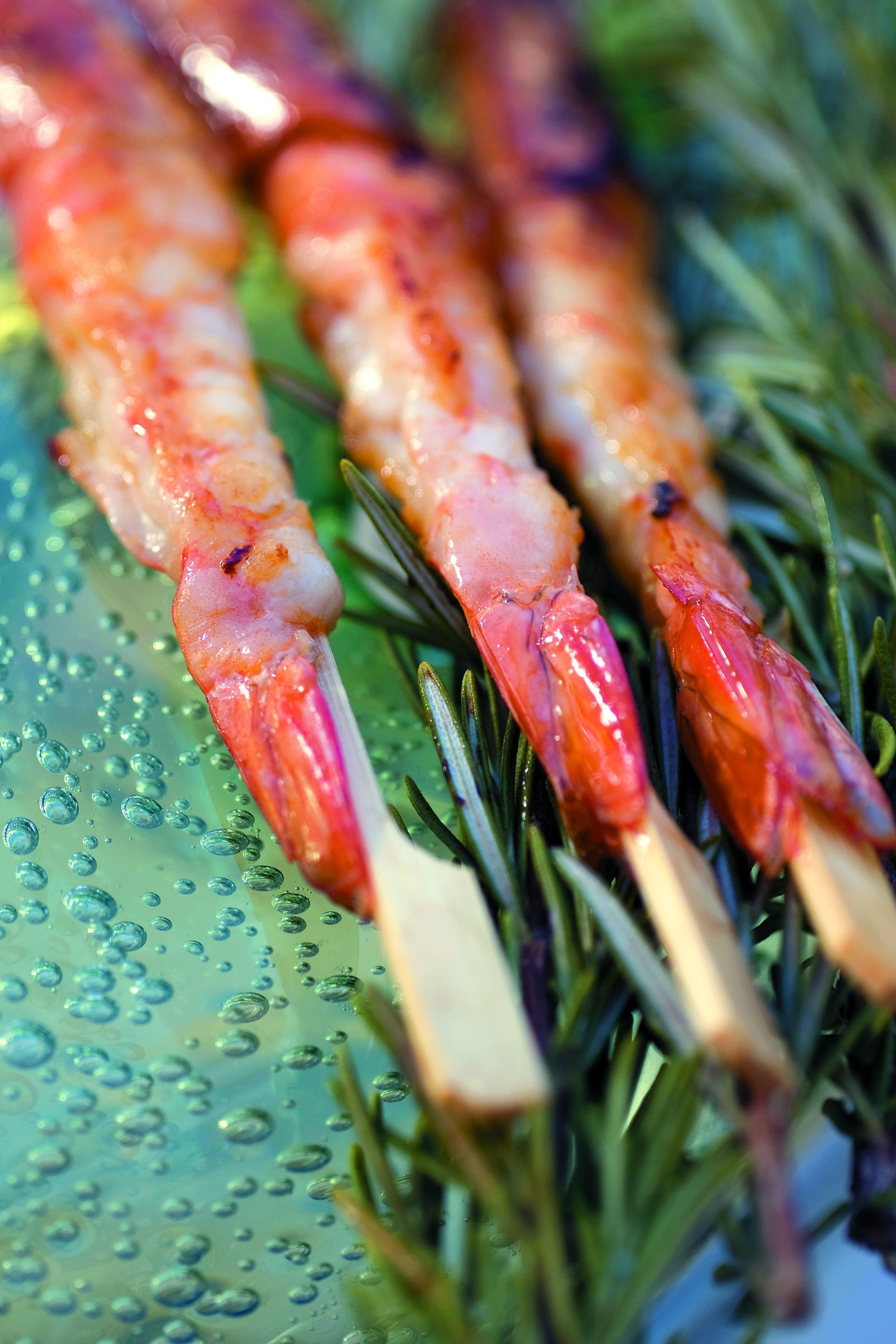 Shrimp skewers on a plate with a green background.