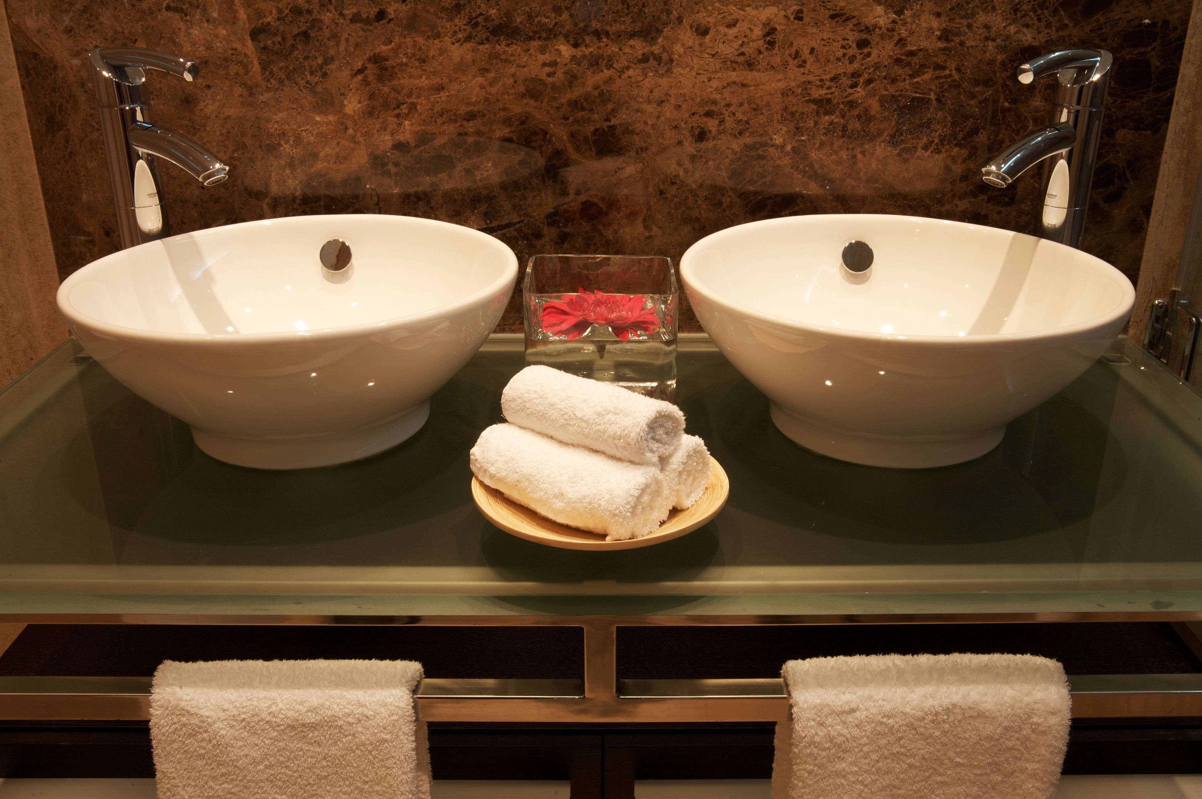 Ein Badezimmer mit zwei Waschbecken, einer Glasabtrennung und einer kleinen Schachtel mit roter Schleife.