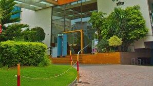 Un hotel con entrada de vidrio, un cartel que dice 'Central Park Hotel' y un jardín bien cuidado.