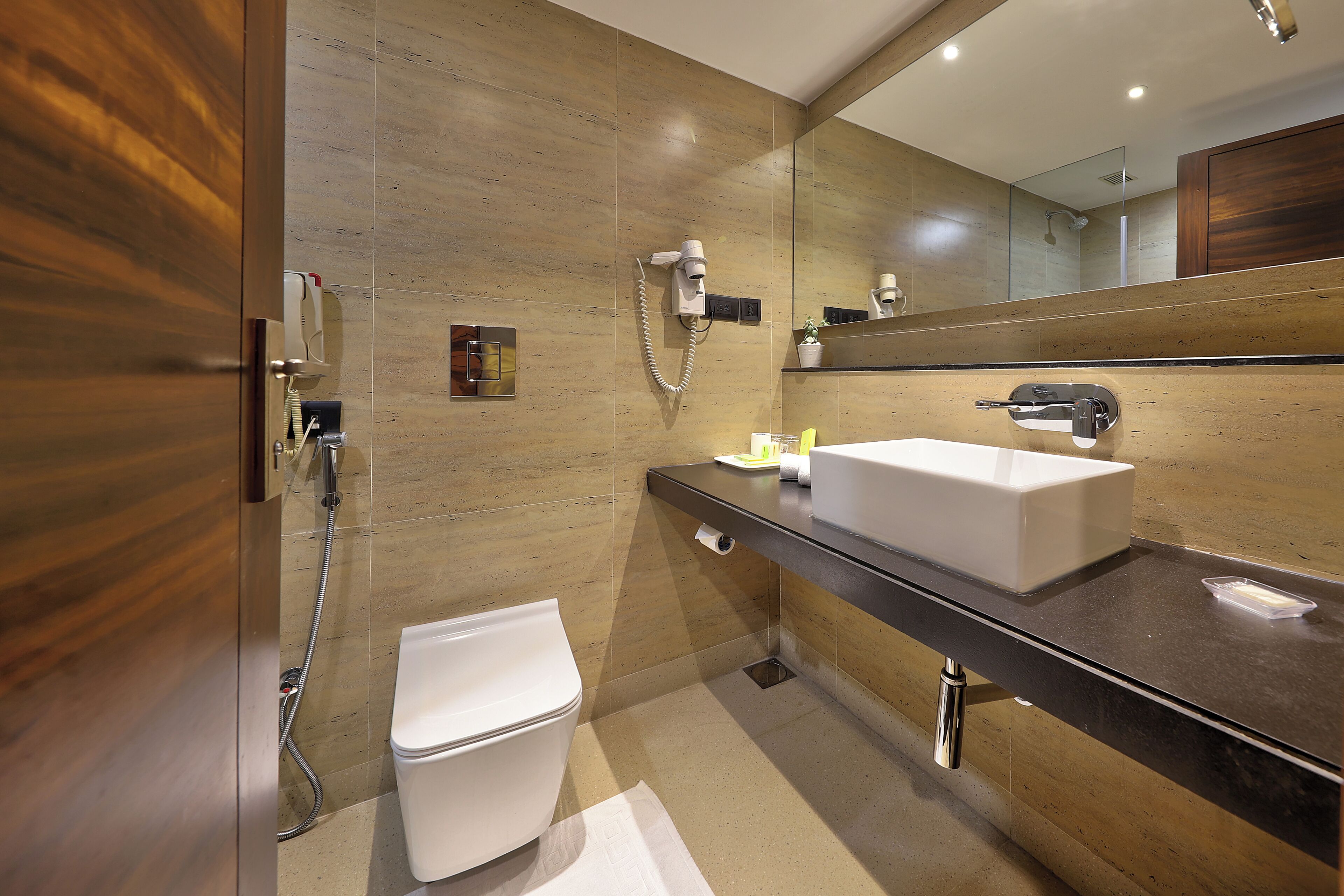 A modern bathroom with a wooden vanity, a white sink, and a large mirror.