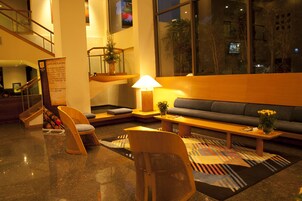 Un vestíbulo moderno con un sofá, sillas, una mesa de centro y una escalera.