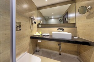 Un baño moderno con encimera negra, lavabo blanco y un espejo grande.