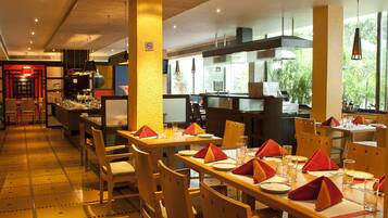 Un restaurant avec des tables et des chaises en bois, des serviettes rouges et un sol carrelé.
