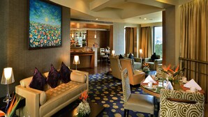 A hotel lobby with a bar, seating area, and a painting on the wall.