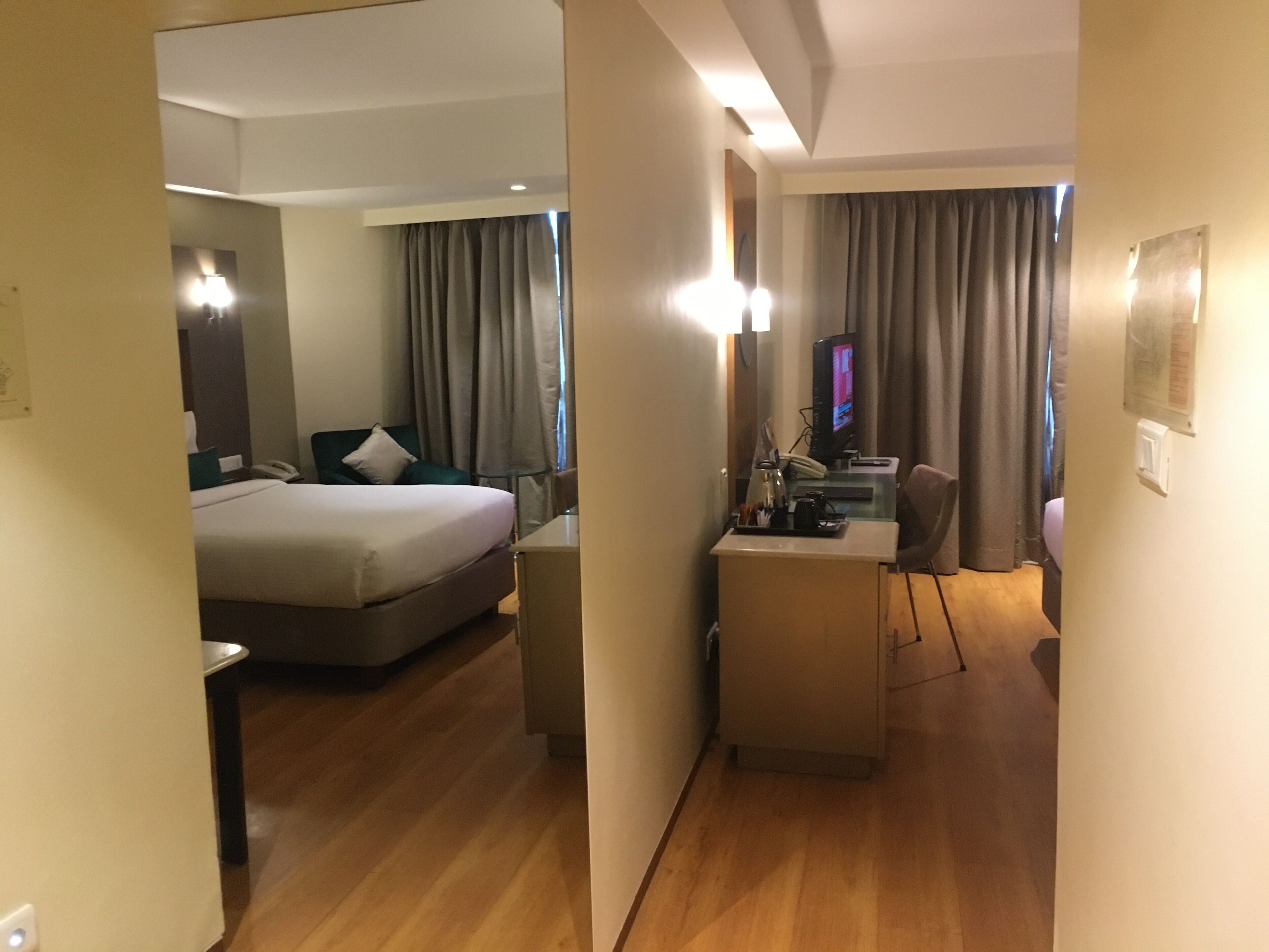 Habitación de hotel con cama, escritorio con ordenador y televisor.