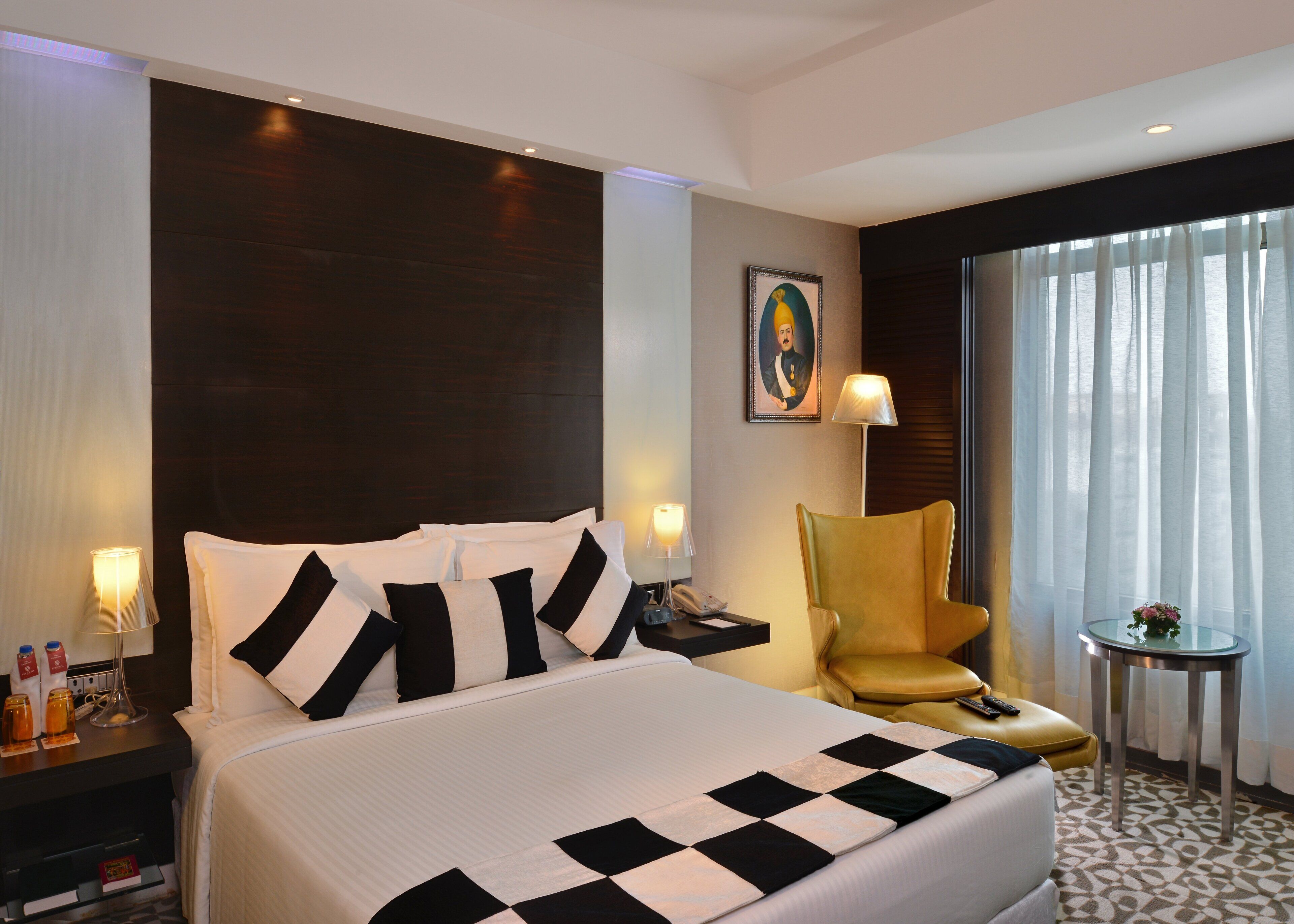 Ein Hotelzimmer mit einem großen Bett, einem Sessel, einem kleinen Tisch und einem Bild an der Wand.
