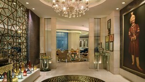 A luxurious lobby with a chandelier, a patterned floor, and a large portrait on the wall.