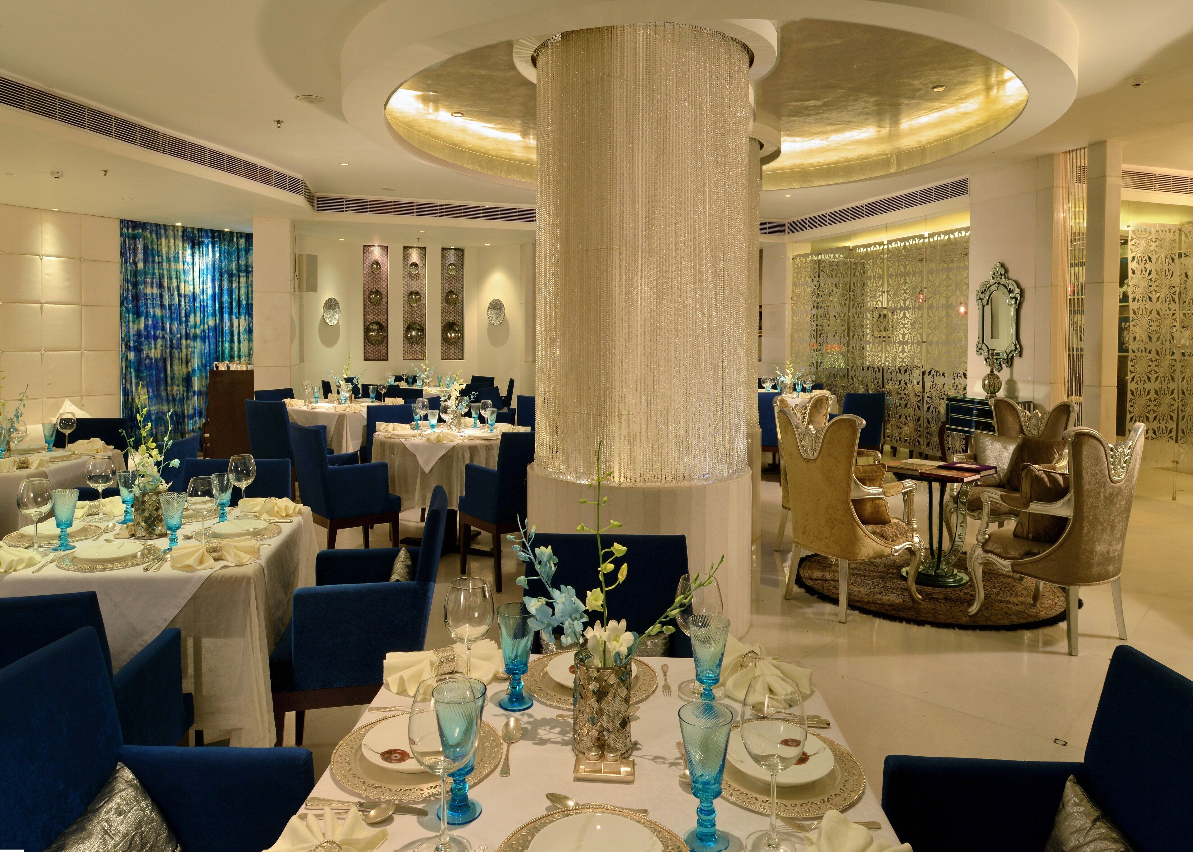 A luxurious dining area with round tables, blue upholstered chairs, and elegant decor.
