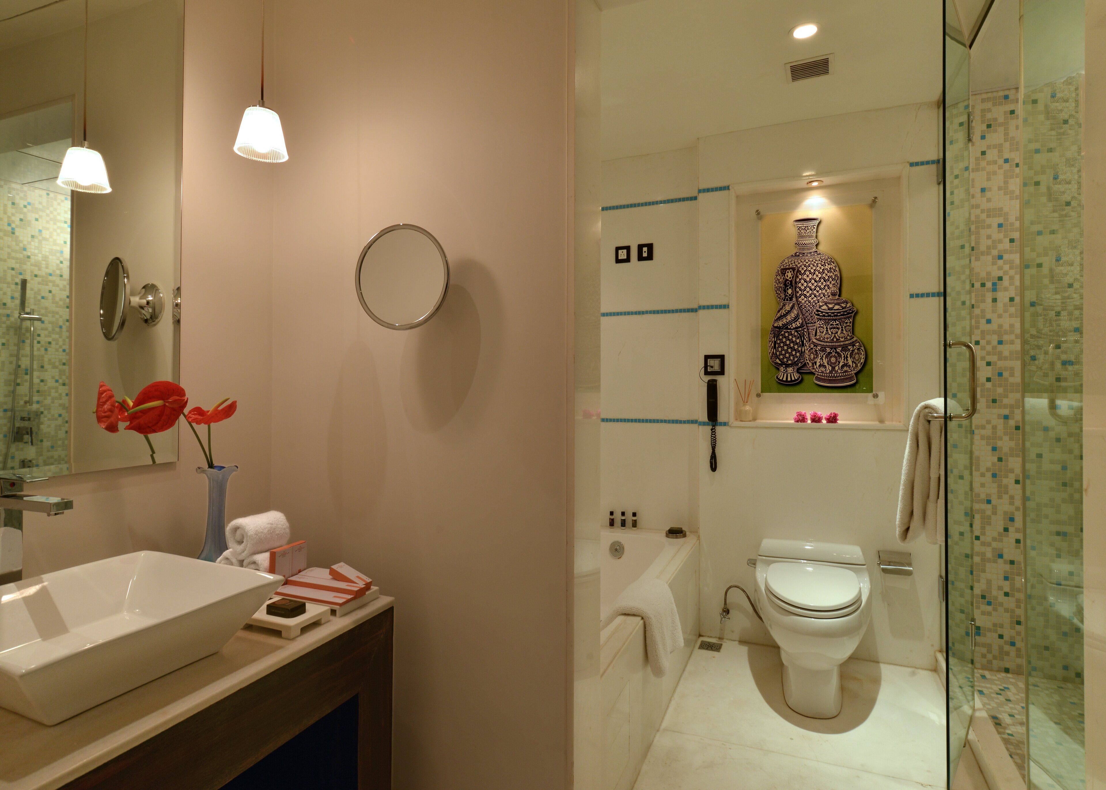 A modern bathroom with a large mirror, a sink, a toilet, and a shower area.