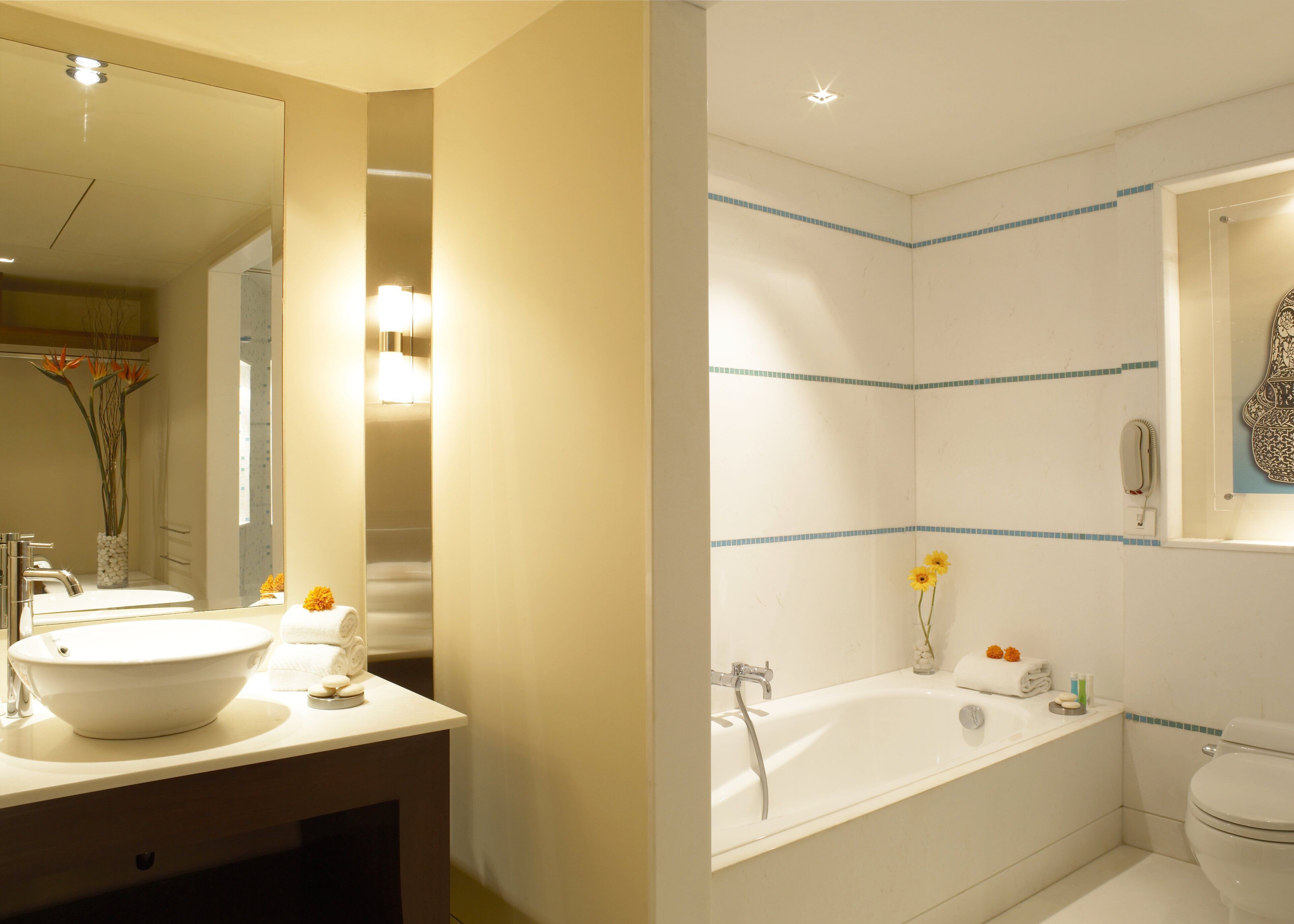 A bathroom with a large mirror, a sink, a bathtub, and a toilet.