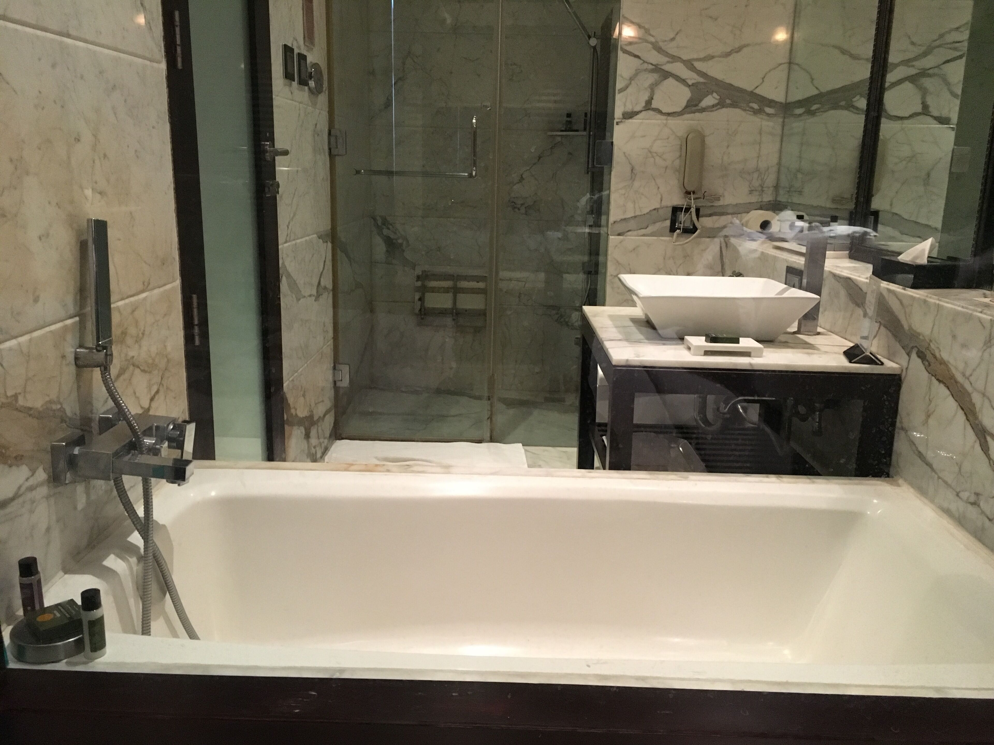 A modern bathroom with a large bathtub, a glass-enclosed shower, and a vanity with a sink and mirror.