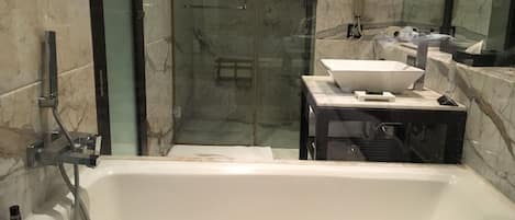 A modern bathroom with a large bathtub, a glass-enclosed shower, and a vanity with a sink and mirror.